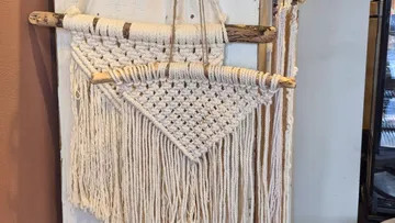 Macramé wall hanging on wooden sticks.