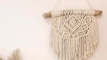 Macrame wall hanging on white wall.