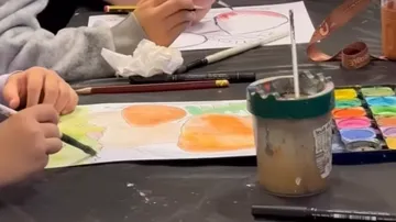 Personen malen am Tisch mit Aquarellfarben.