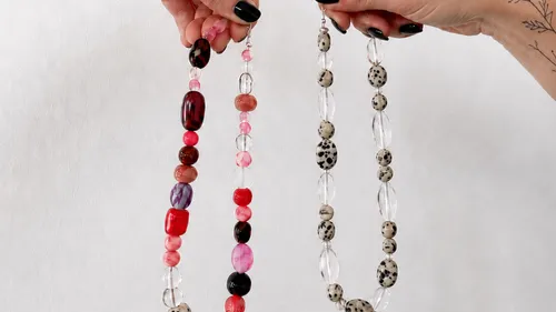 Hands holding two colorful beaded necklaces.