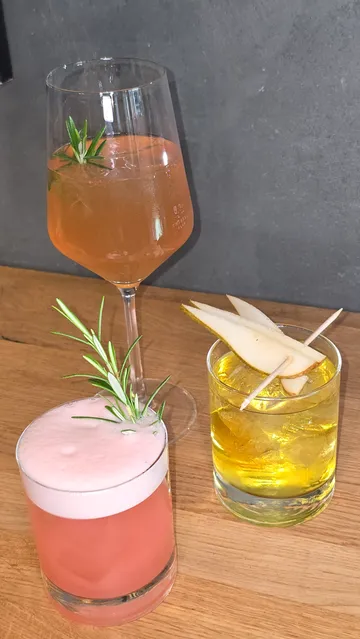 Drei Cocktails auf einem Holztisch.