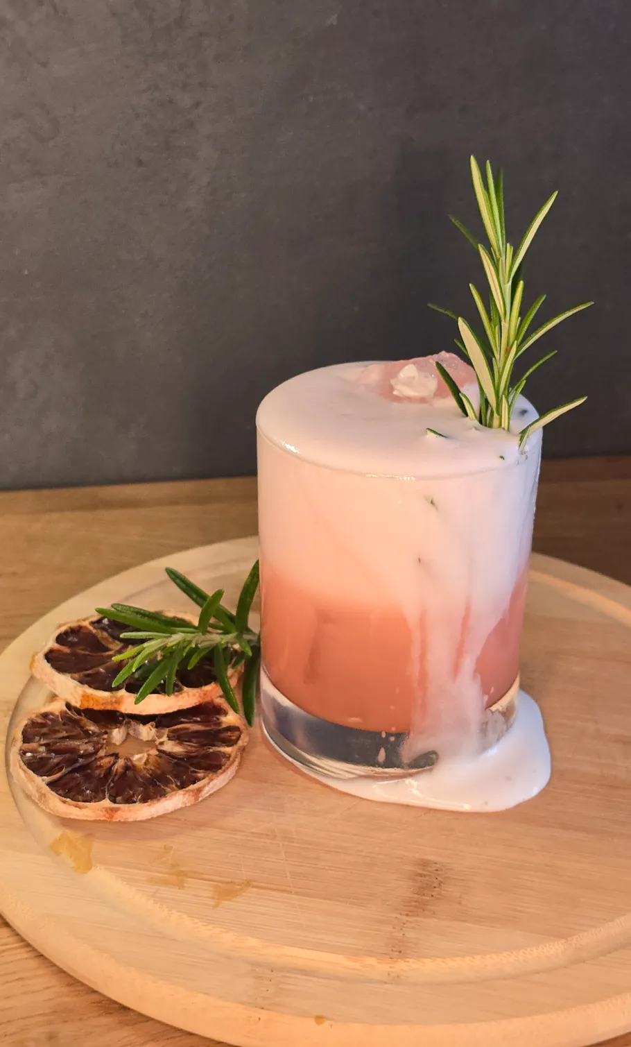 Cocktail mit Schaum auf rundem Holzbrett.