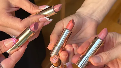 Fünf Hände halten verschiedene Lippenstiftfarben.