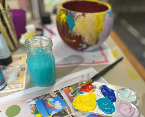 Farbglas und Palette auf Basteltisch.