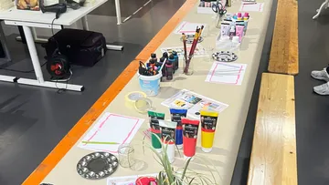 Kunstbedarf auf einem langen Tisch drinnen angeordnet.