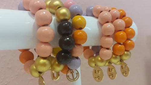 Colorful bead bracelets displayed on a white stand.