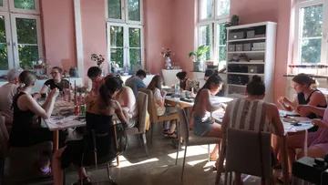 People painting in a sunlit room.