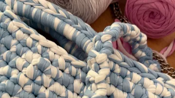 Crocheted blue bag with yarn spools nearby.