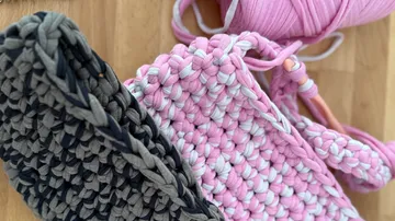 Crocheted items with yarn on wooden surface.