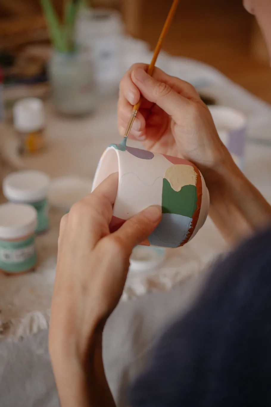 Hände bemalen bunte Keramik drinnen.