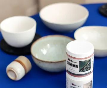 Ceramic bowls and jars on blue surface.