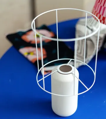Metal frame encloses white can on blue table.