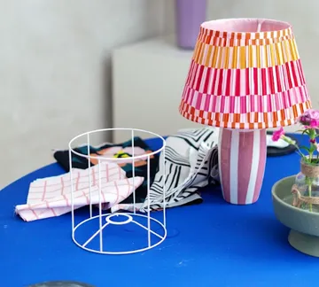 Vibrant lamp on blue table with fabric pieces.