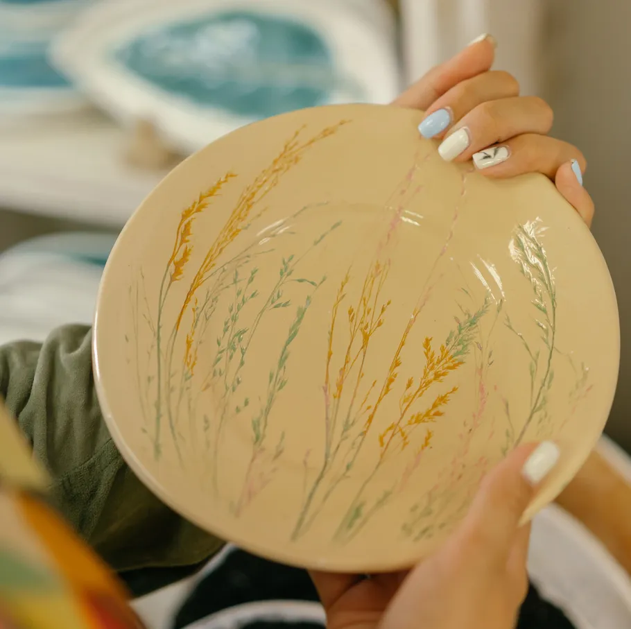 Hands holding plate with floral design.