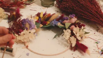 Trockenblumenkranz wird auf Tisch gebastelt.