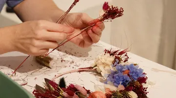 Hände erstellen Blumenarrangement auf Tisch.
