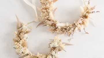 Zwei Blumenkränze mit Trockenblumen an Wand.