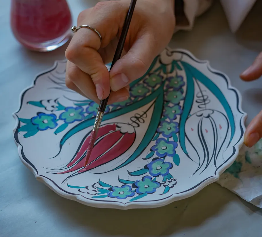 Hand painting floral design on ceramic plate.