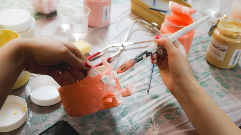 Hands painting a dental model, jars around.