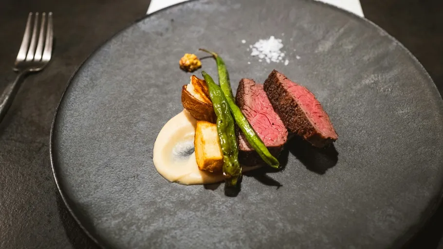Steak with vegetables on black plate.