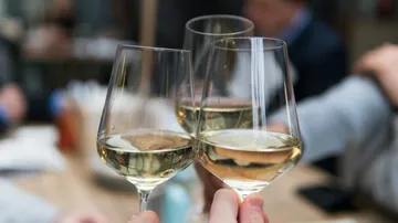 Wine glasses toasting in a social setting.