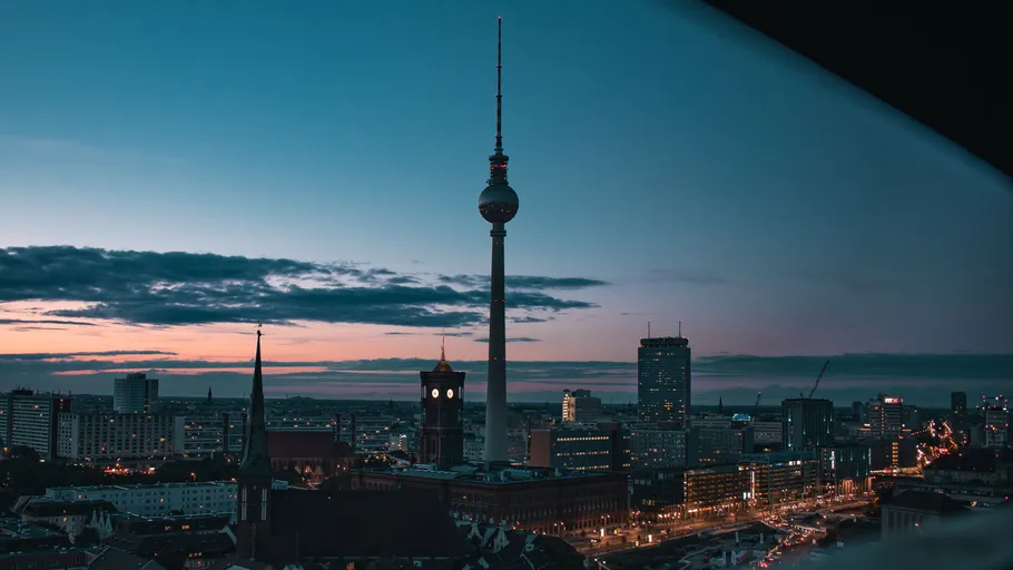 TV tower stands among city buildings at dusk.