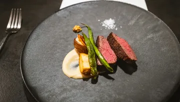 Gourmetsteak mit Gemüse auf dunklem Teller.