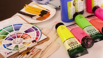 Art supplies including paints and brushes on table.