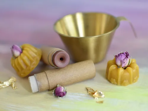 Wax candles and containers arranged on a pastel background.