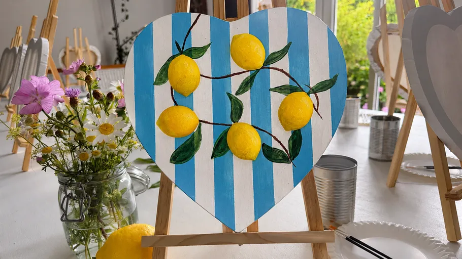 Herzförmige Tafel mit Zitronen auf Staffelei bemalt.