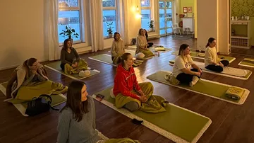 People meditating on mats in cozy room.