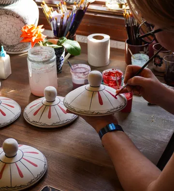 Person painting ceramic lids red in studio.