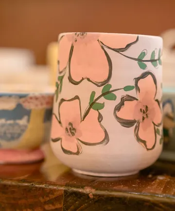 Keramikbecher mit Blumendesign auf Tisch.