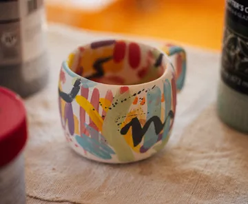 Bunter Becher mit abstraktem Design auf Tisch.