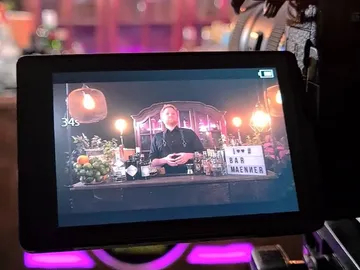 Bartender steht hinter Bar und präsentiert Getränke in stilvollem Ambiente.