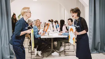 Zwei Frauen zeigen Gemälde im Kunstkurs.