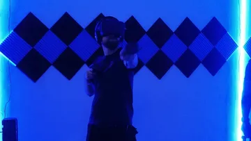 Person mit VR-Headset in blau beleuchtetem Raum.