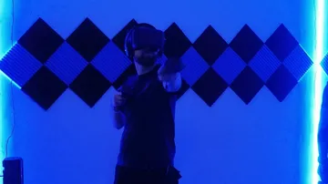 Person using VR headset in blue-lit room.