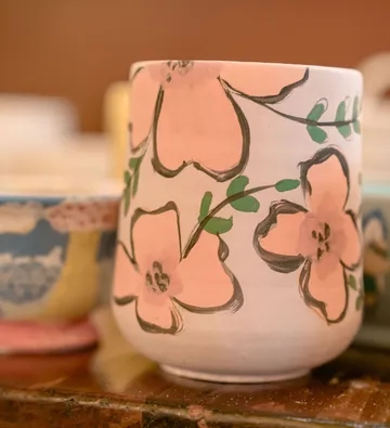 Ceramic mug with pink floral design, indoors.