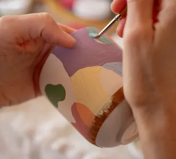 Hands painting colorful design on ceramic.