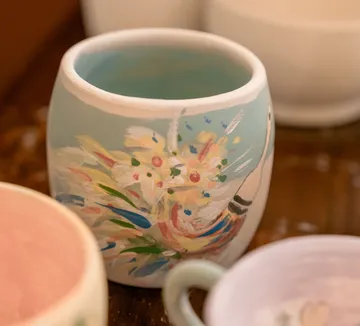 Bemaltes Keramikbecher mit Blumendesign.