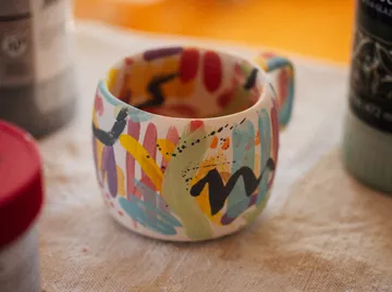 Bunt bemalter Becher auf einem Tisch.