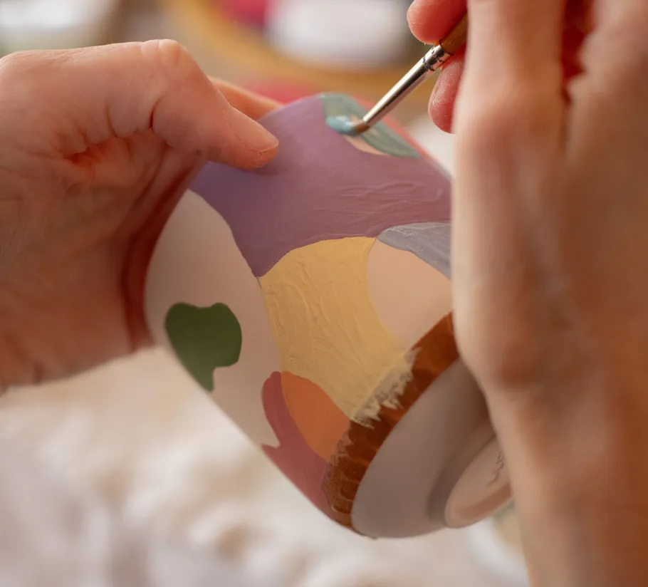 Hände bemalen bunte Keramiktasse.