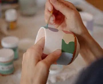 Hände bemalen bunte Keramiktasse.