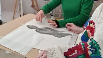 Hände skizzieren auf Papier im Kunststudio.