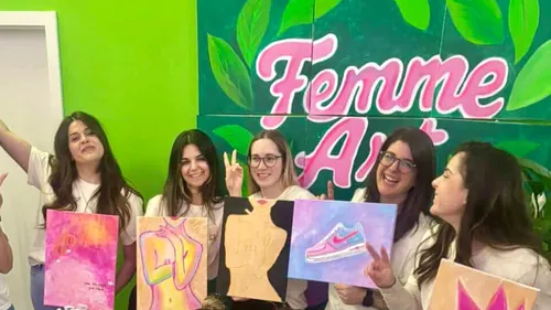 Gruppe von Frauen zeigt Gemälde drinnen.