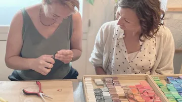 Zwei Frauen machen Schmuck an einem Tisch.