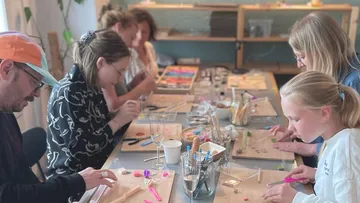Personen basteln an einem Tischworkshop.