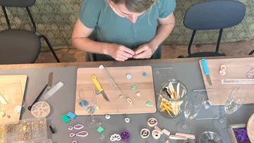 Woman crafting jewelry at a table.