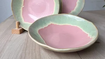 Ceramic plates with pink center, wooden table.